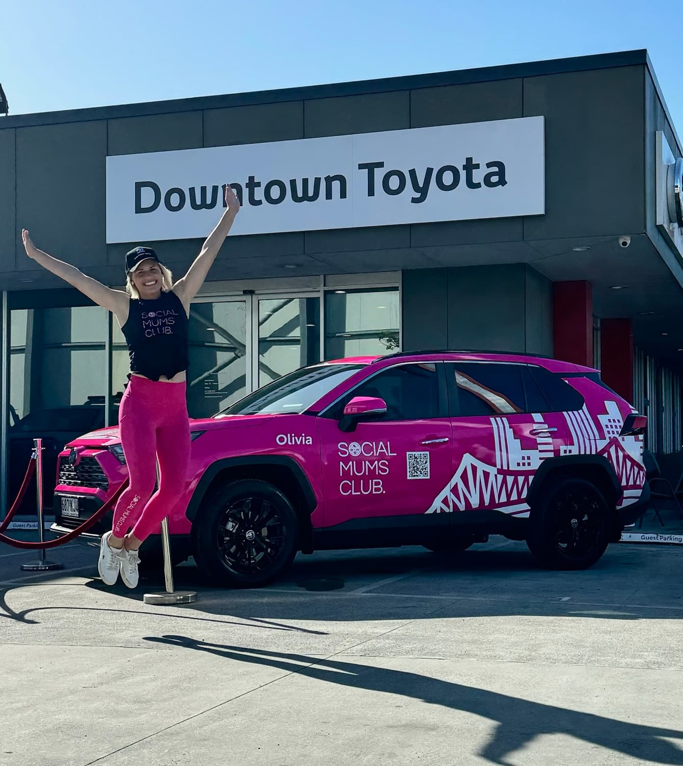 Kirsty Foster jumping in front of Olivia the Social Mums Club pink Toyota RAV4 at Downtown Toyota